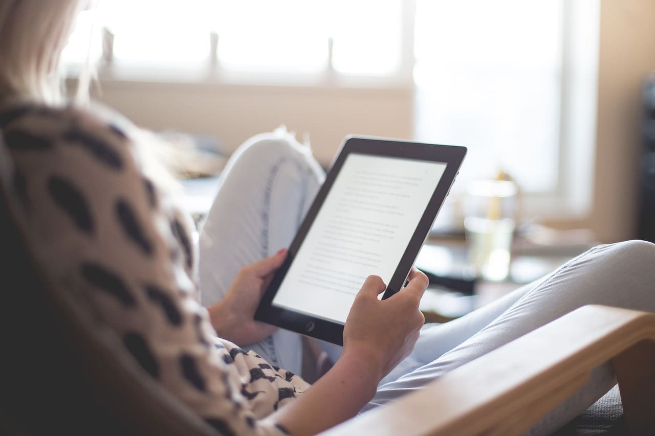 A person sitting at a table with an e-reader.